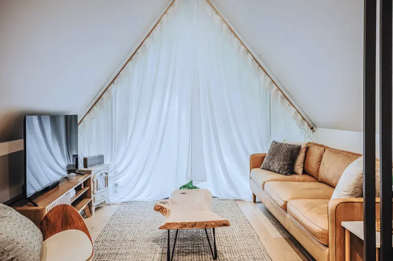 Floor-to-peak sheer curtains on the A-frame window wall